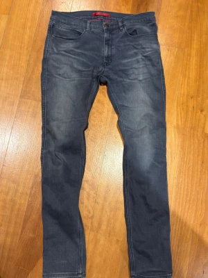 Hugo boss jeans - Snygga mörkblå slim fit jeans med lätt slitning på framsidan och klassiska fem fickor. Jeansen har raka ben och är tillverkade i stretchigt denimtyg för extra komfort. Passar perfekt till en avslappnad stil.