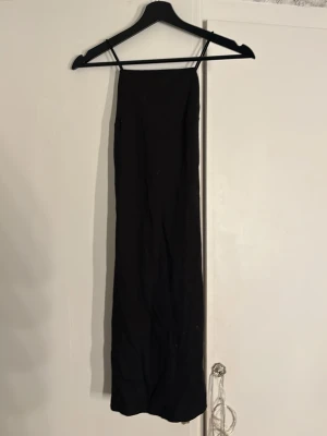 Kort tajt klänning med kors i ryggen - En simpel kort svart klänning, banden går i kors bak i ryggen. Endast använd 1 gång 💞 pris kan diskuteras 🤩