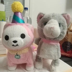 Två söta gosedjur katt och hund / båda för 10 kr - Två mjuka gosedjur, en gråvit katt med rosa halsband och en rosa-vit hund med stickad tröja, halsduk och partyhatt med gul boll. Perfekta som dekoration eller present till någon som älskar gulliga mjukdjur.