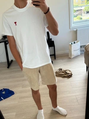 Vit t-shirt med rött hjärta och A - Vit t-shirt i bomull med ett broderat rött hjärta och bokstaven A på bröstet. Enkel och stilren design som passar perfekt till jeans eller shorts. Broderiet ger en snygg detalj som sticker ut.