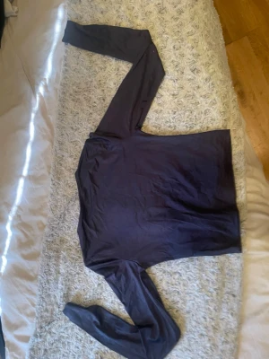 Mörkblå långärmad basic topp - En enkel och stilren mörkblå långärmad topp i lent och stretchigt material. Modellen är rak med rund halsringning och passar perfekt till jeans eller kjol. Perfekt basplagg för garderoben.