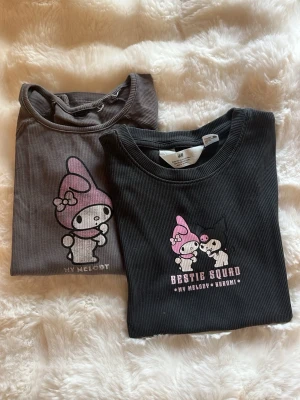 Svart My Melody och kuromi t-shirt  - Svart ribbad t-shirt från H&M med tryck av My Melody och Kuromi samt texten 'Bestie Squad'. T-shirten har korta ärmar och rund hals. Perfekt för dig som gillar söta och lekfulla motiv. Tröjan med kuromi är i storlek 170 och tröjan med bara my melody har ingen lapp men sitter likadant som kuromi tröjan bara lite bredare i midjan. Tror my melody tröjan säljs som pyjamas ☺️sitter som en xs. Kan köpas enskilt my melody för 30kr och kuromi tröjan 40kr.