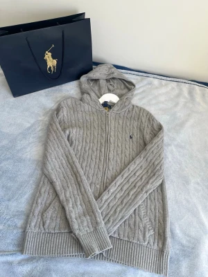 Grå🩶 stickad hoodie Polo Ralph Lauren - Snygg grå🩶 kabelstickad hoodie från Polo Ralph Lauren i storlek 18-20xl. Skriv vid minsta intresse 😁Priset är inte hugget i sten 🪨 