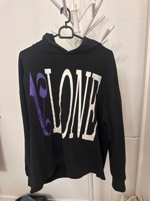Palm Angeles hoodie x vlone - Snygg svart hoodie med stor vit och lila VLONE-print på framsidan och coolt vitt flamemönster längs ena ärmen. Oversized passform och huva. Perfekt för dig som gillar streetwear och vill sticka ut med en unik design.  . Endas handtvätt. Från la 