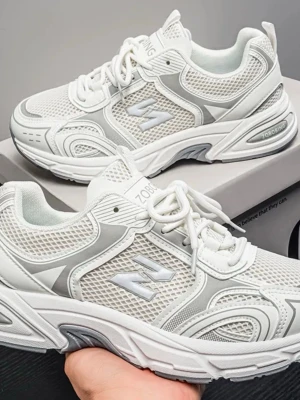 Vita mesh sneakers med grå detaljer - Snygga vita sneakers med grå detaljer och meshpaneler för extra ventilation. Skorna har en chunky sula och coola mönster längs sidorna. Perfekta för dig som gillar sportig och trendig stil. Klassisk snörning och bekväm passform.