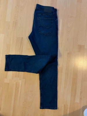 Mörkblå slim fit jeans - Snygga mörkblå slim fit jeans med klassisk femficksdesign och raka ben. Jeansen har en enkel bakficka och är tillverkade i ett stretchigt denimtyg som ger en bekväm passform. Perfekta för en avslappnad och trendig look.