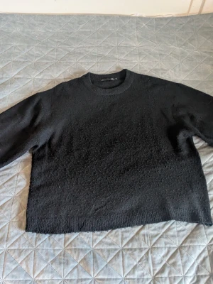Svart stickad tröja - En svart stickad tröja med rund hals och ribbade muddar. Använd men fortfarande i bra skick endast lite nopprig