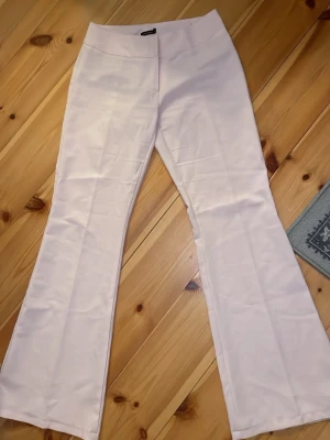 Ljusrosa kostymbyxor Vero Moda - Säljer ett par ljusrosa kostymbyxor från Vero Moda. Byxorna har utsvängda ben och hög midja. Snygga men de är lite genomskillniga så man är medveten om det!!!💕
