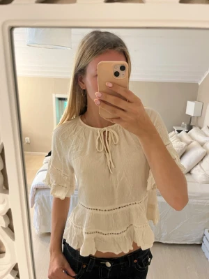 Vit blus med volanger och knyt - Söt vit blus från Vila med volangdetaljer och knyt i halsen. Tillverkad i ett lätt och luftigt material💗