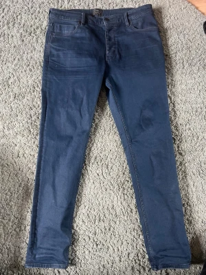 Denim jeans  - Snygga mörkblå slim fit jeans med klassisk femficksdesign och normal midja. Jeansen har raka ben och är tillverkade i ett stretchigt denimtyg som ger en bekväm passform. Perfekta för en stilren och avslappnad look.