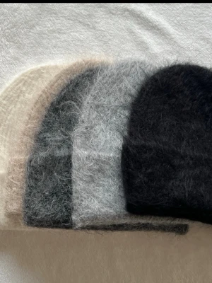  fluffiga mohairmössor - Säljer flera mjuka och fluffiga mössor i mohairmix. Finns i färgerna svart, grå, beige, offwhite och mörkgrön. Klassisk form med ribbad kant, perfekt för kalla dagar. Mössorna har en trendig, luddig finish som ger en mysig look. 499kr/st 