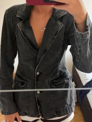 Svart denimkavaj med markerad krage - Snygg svart kavaj i denim med markerad krage och två knappar framtill. Har vaddering i axlarna. Enbart använd en gång  Passar en Xs också❣️