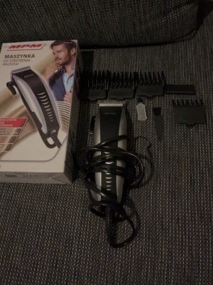 MPM hårtrimmer med tillbehör - Elektrisk hårtrimmer från MPM i svart och silver med flera utbytbara kammar, rengöringsborste och olja. Perfekt för styling och trimning av hår. Ergonomisk design med sladd för enkel användning. Levereras med originalkartong.