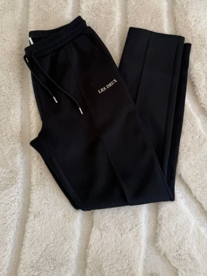 Svarta mjukisbyxor från Les Deux - Snygga svarta mjukisbyxor från Les Deux med snöre i midjan och diskret logga på benet. Byxorna är breda men följer benets form💗