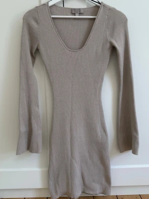 Beige ribbad långärmad klänning - Säljer en beige, ribbad klänning med lång ärm och djup rundringning. Klänningen är figurnära och har en mjuk, stretchig känsla som passar perfekt till många olika stilar💗