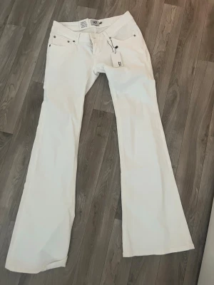 Vita utsvängda jeans i full längd low waist - Snygga vita jeans med utsvängda ben och klassisk femficksmodell. Jeansen är i full längd och har en stilren look som passar till många olika outfits. Perfekta för dig som gillar en trendig och fräsch stil.