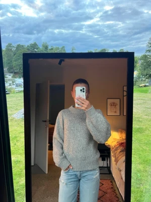 Grå stickad tröja  - Mysig grå stickad tröja med rund hals och ribbade muddar vid ärmslut och nederkant. Tröjan har en avslappnad passform och är perfekt för kyliga dagar. Passar till jeans eller kjol för en enkel och stilren look. Skriv för frågor🩷🫶🏼