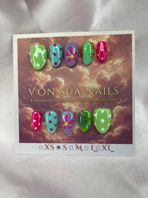 Pogo (S);ExtraShortAlmond  - Färgstarka handgjorda press-on nails i grönt, turkost, lila och rosa. Setet har lekfulla prickar, upphöjda blomdetaljer och handmålade fiskmotiv. Ett kul och färgstarkt set där varje nagel har sin egen detalj.  Storlek: S 10 naglar ingår