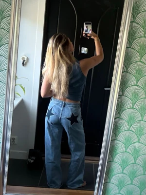 Blå jeans med stjärnor bak - Säljer ett par ljusblå jeans med raka ben och hög midja. På bakfickorna finns stora mörk blåa stjärnor💙⭐️för referens är jag 164cm lång, använda max 3 gånger!! (Nypris 623kr)