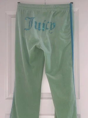 Gröna Juicy Couture mjukisbyxor med blå detaljer - Gröna Juicy Couture mjukisbyxor med blå detaljer. Bra skick men med några små fläckar (se bild 3 och 4). Har ej använt dem då de är för långa. Storlek S men mjukisbyxor är stretchiga så de passar minde och större storlekar också. Byxorna har 3 fläckar, vet att de går bort men därför är jag villig att diskutera  och eventuellt sänka priset (hör av dig isåfall) 🚨Tar bara emot betalningar via Swish!!! Om du vill ha fler bilder eller har frågor är det bara att skriva till mig!!!🚨