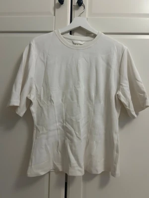 Vit basic t-shirt i bomull - Aldrig använt tröja från hm. En enkel och stilren vit t-shirt med rund hals och korta ärmar. Tillverkad i mjuk bomull för en skön känsla och passar perfekt till alla outfits. Klassisk passform och tidlös design.