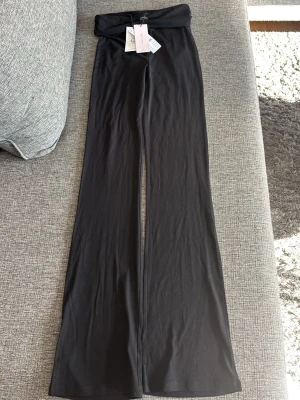 Svarta leggings från Gina Tricot Young - Snygga svarta leggings från Gina Tricot Young med utsvängda ben och låg midja. Tillverkade i mjukt och stretchigt material som sitter skönt på kroppen. Perfekta för en trendig och avslappnad look.