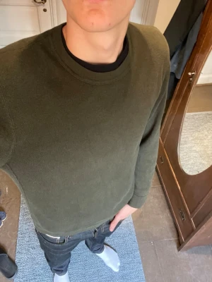 Olivgrön basic sweatshirt - En enkel och stilren olivgrön sweatshirt med rund halsringning och långa ärmar. Tröjan har en relaxed fit och är tillverkad i mjukt material, perfekt för en chill och avslappnad look.