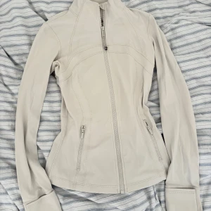 Cremevit träningsjacka från Lululemon - Dfyne jacket från Lululemon som inte kommer till användning. Använd få gånger. Nyskick, storlek 4. 