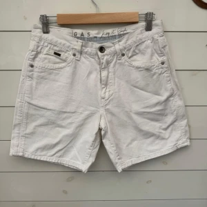 Vita bomullsshorts från GAS - Snygga vita shorts från GAS i mjuk bomull. Klassisk femficksmodell med knappgylf och bälteshällor. Perfekta för sommaren och passar till det mesta. Enkel och stilren design med diskret logga på bakfickan.0212