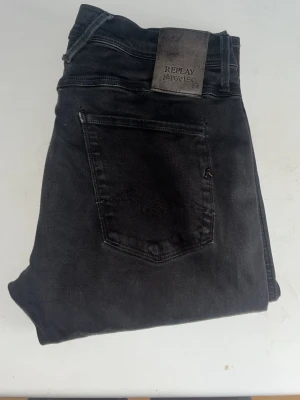 Reglat hyperflex jeans  - Svarta Replay Hyperflex jeans med slim fit och klassisk femficksdesign. Jeansen har stretchigt material för extra komfort och en snygg, smal siluett. STORLEKSLAPPEN ÄR BORTA jag bedömer storleken till W30 och L32 baserat på måtten så kolla dom noggrant . Ifall det inte finns någon bild i annonsen där jag bär plaggen jag säljer så är det för att jag ej kan ha storleken heller passformen, så kolla måtten för storlek och googla på modellnamnet för passform 😉(r15)