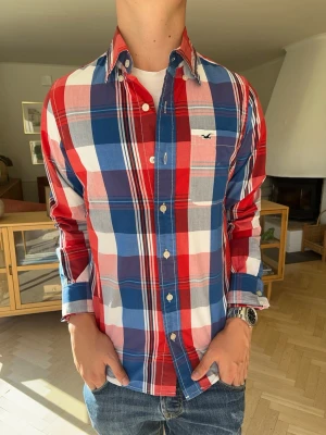 Hollister skjorta herr rutig vintage  - Färgglad rutig skjorta från Hollister i rött, blått och vitt. Klassisk button down-krage och märkets ikoniska logga broderad på bröstfickan. Perfekt till ett par schyssta jeans för en avslappnad men välklädd stil. Mjukt tyg med skön passform. I mycket fint skick!#hollister #skjorta #rutigskjorta #plaid #buttondown #preppy #streetwear #menswear #casual #vintedse