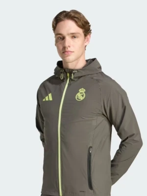 Grå vindjacka med huva Real Madrid - Snygg grå vindjacka med huva och dragkedja framtill. Jackan har limegula detaljer, Real Madrid-logga och Adidas-märke på bröstet. Tillverkad i lätt, vindtätt material och har två sidofickor med dragkedja. Perfekt för blåsiga dagar.