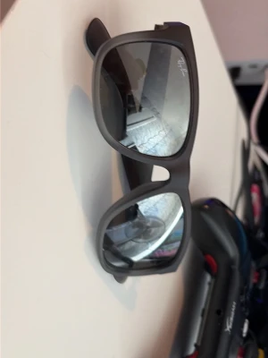 Svarta solglasögon från Ray-Ban - Snygga svarta solglasögon från Ray-Ban med klassisk rektangulär form. Bågarna är i plast och glasen är mörka, perfekta för soliga dagar. En ikonisk accessoar som lyfter vilken outfit som helst.