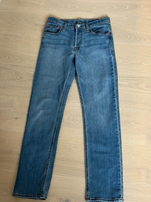 Blå raka jeans med klassisk passform - Säljer ett par blå Levis jeans för junior med rak passform och normal midja. Jeansen är storlek 14. Skulle säga att det passar ålder ca 13-15 år. Gott skick utan slitage, knappt använda. 