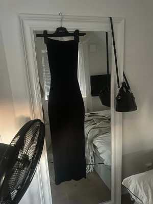 Svart långklänning axelbandslös - Säljer en svart, figurnära långklänning med axelbandslös design. Klänningen har en enkel och stilren siluett som framhäver kroppen. Perfekt för dig som gillar minimalistisk och elegant stil.