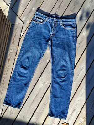 Blå raka jeans Arket - Säljer ett par klassiska blå jeans med rak passform. Jeansen har normal midja,. Materialet är denim i bomull och färgen är mellanblå med lätt slitning som man ser vid bild