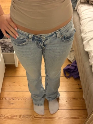 Ljusblå bootcut jeans med låg midja - Säljer ett par ljusblå bootcut jeans med låg midja. Jeansen har snygga och detaljerade bakfickor med knapp. Perfekta för en avslappnad och trendig look🤩🙌