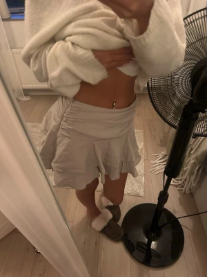 Beige volangkjol med omlottkänsla - Säljer en ljusbeige kortkjol med volangdetaljer och omlottkänsla. Kjolen har en flowy passform och är perfekt för varmare dagar. Materialet känns lätt och luftigt, vilket gör den skön att bära. Passar till många olika stilar och outfits. Har även inbyggda shorts och dragkedja på sidan. Köpte i M för att de andra storlekarna var slut men funkar som en S. Knappt använt. 