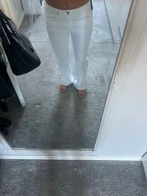 Vita raka jeans - Säljer ett par vita jeans med rak passform. Jeansen har klassisk femficksdesign och stängs med knapp och dragkedja. Perfekta för en clean och fräsch look till sommaren.