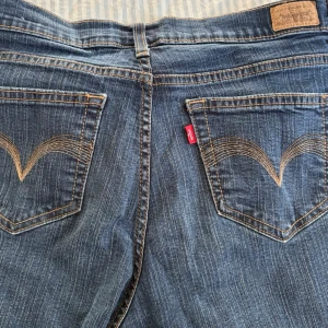 Vintage Levi's 512 Straight blå jeans - Säljer ett par klassiska vintage blå Levi's 512 Straight jeans med snygga kontrastsömmar och ikoniska bakfickor med broderad båge. Modellen är 'Perfectly Slimming' och har normalhög midja. Tillverkade i slitstarkt denim med knapp och dragkedja framtill. Storlek 12 medium. US 12 ≈ EU 42 ≈ W31–W32 ≈ Medium/Large. Köpta från beyond retro.