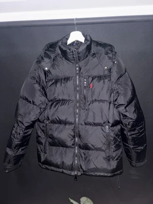 Ralph Lauren Vinterjacka - Väldigt fin jacka från Polo Ralph Lauren. Använd under en säsong. Enda defekten är att spännbandet på ena sidan har gått sönder, men väldigt lätt att sy ihop igen. 