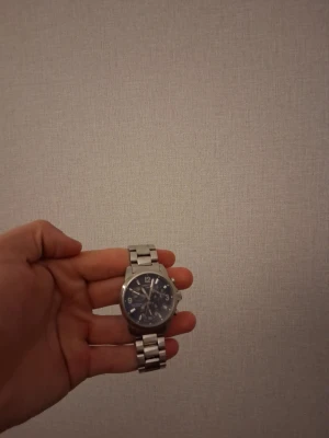 Certina klocka FUNKAR EJ  - Stilren Certina klocka i silver med metallarmband och rund urtavla. Urtavlan är mörk med tydliga siffror och flera små visare för extra funktioner. Perfekt accessoar för dig som gillar en tidlös look. FUNKAR EJ men funkar om man går till närmaste klock butik och ber dem fixa de är inte DYRT. 