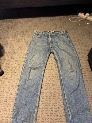 Ljusblå raka jeans från Karve - Ljusblå jeans från Karve med klassisk femficksdesign och raka ben. Jeansen har bälteshällor och synliga sömmar i kontrastfärg. Perfekta för en avslappnad och trendig look. Obs en trasig innerficka men går lätt att sy!