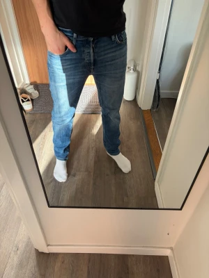 Blå straight fit jeans jack & jones  - Säljer ett par blå jack and Jones jeans med klassisk femficksdesign och snygg tvätt. Jeansen har normal midja och raka ben, perfekt för dig som gillar en modern och enkel stil. Materialet är mjukt och bekvämt denim.