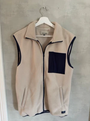 Beige fleeceväst med blå detaljer Blend - Säljer en beige fleeceväst från Blend med marinblå detaljer, hel dragkedja och hög krage. Västen har en stor blå bröstficka och två sidofickor. Perfekt för lager-på-lager och chill stil. Skick 9/10, Storlek S, hör av dig vid frågor 🙌
