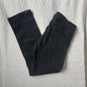 Svarta jeans från Wrangler - Säljer ett par snygga svarta jeans från Wrangler. De har klassisk femficksdesign, raka ben och är gjorda i slitstarkt denim-material. Perfekta för dig som vill ha ett stilrent och tidlöst plagg i garderoben.