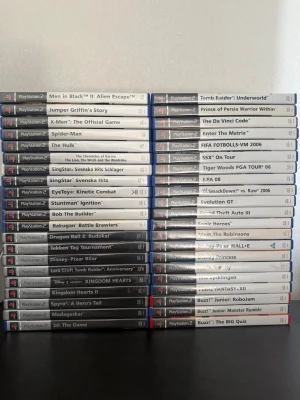 Samling PlayStation 2 spel - Stor samling PlayStation 2 spel med titlar som Kingdom Hearts, Dragon Ball Z: Budokai, Tekken Tag Tournament, Tomb Raider, Spider-Man och många fler. Spelen har blå plastfodral och klassisk PS2-design. Perfekt för dig som vill bygga ut din retrospelsamling eller återuppleva gamla favoriter.