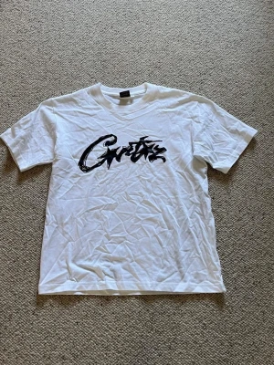 Corteiz T-shirt  - En vit Corteiz T-shirt med svart text rakt över. Den är i storlek S och i nytt skick. Pris kan diskuteras och skriv om du har några frågor. 