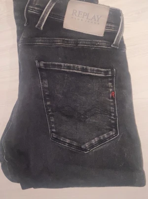 Svarta Replay jeans med tvättad look - Säljer ett par svarta jeans från Replay med snyggt tvättad look och klassisk femficksmodell. Jeansen har en diskret logga på bakfickan och patch med Replay-märke i midjan. Perfekta för dig som gillar en avslappnad men stilren stil.Dyraste replay jeansen vi har haft än, Och är i ett jätte bra skick