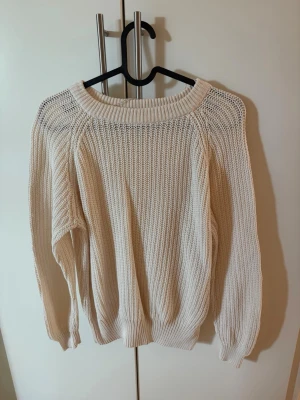 Beige stickad/virkad tröja - Säljer en beige stickad tröja med bred ribbad rund halsringning och långa ärmar. Tröjan har en grovstickad struktur och ribbade muddar vid ärmslut och nederkant. Storlek s men skulle säga att den är liten i storlek, så typ xs